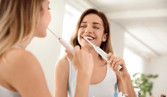 Woman brushing teeth to prevent dental emergencies