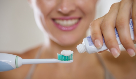 Woman putting toothpaste on toothbrush to brush teeth