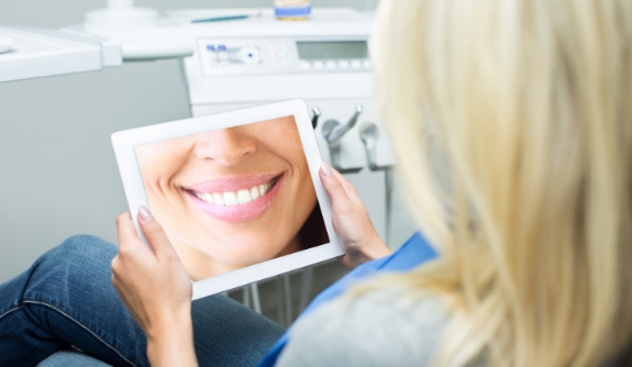 Woman looking at digital smile imaging on tablet computer