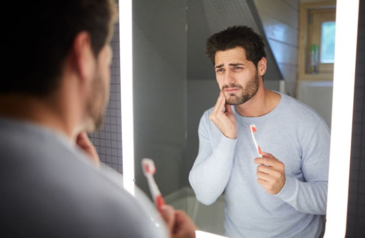 Man in need of emergency dentistry holding jaw in pain