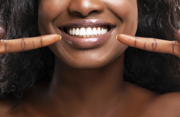 Woman pointing to healthy smile after gum disease treatment