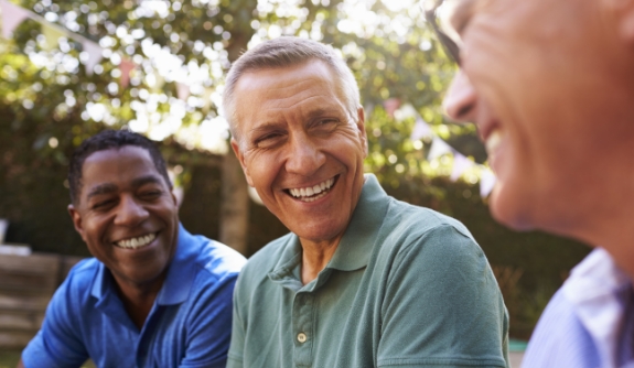 Man smiling with friends after tooth replacement with dental implants