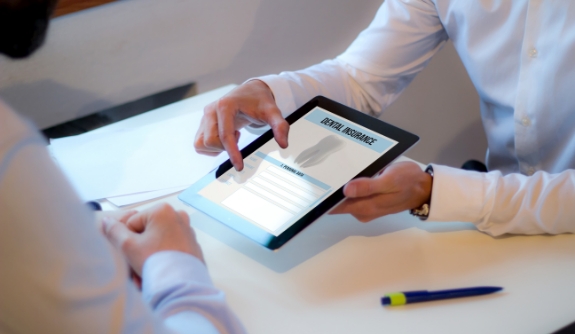 Dentist showing patient dental insurance forms on tablet computer