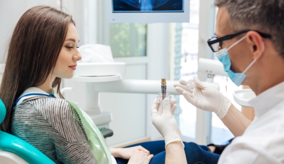 Dentist and patient looking at dental implant model