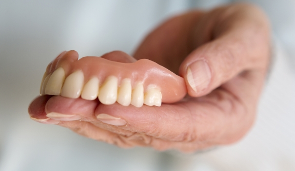 Hand holding full dentures