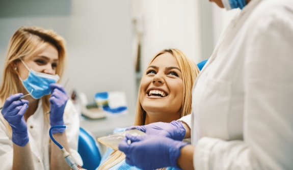 Woman smiling at dentist and dental team member during root canal treatment