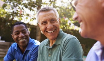 Man sharing flawless smile with friends after replacing missing teeth