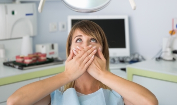 Fearful patient in need of sedation dentistry covering her mouth