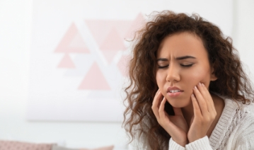 Woman in need of emergency dentistry covering her mouth