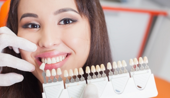 Dentist comparing porcelain veneer shades to natural tooth coloring